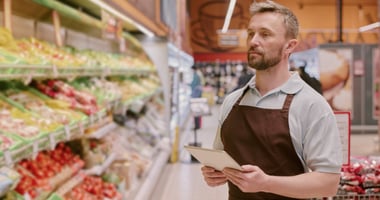 Grocery store clerk monitoring produce. 